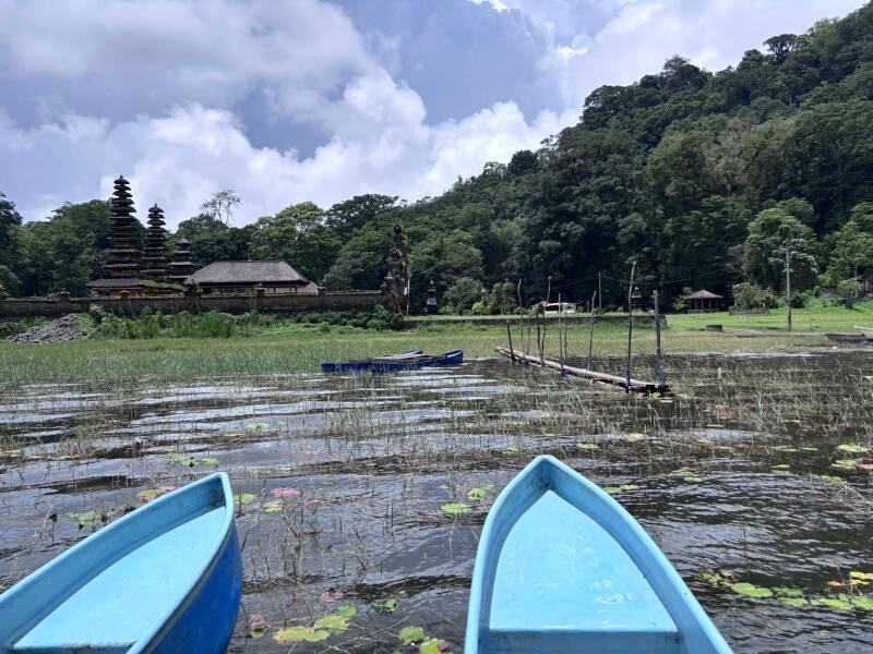 Barques bleues amarrées devant un temple au bord du lac Beratan